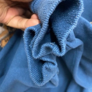 May include: Close-up of the inside of a blue sweatshirt cuff. The fabric is soft and textured.