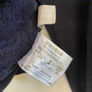 Może przedstawiać: Biała metka z czarnym tekstem, kt&oacute;ry brzmi "UNIQLO Haring Estate. 346-016468(43-01)" i podaje skład tkaniny jako 100% bawełna i 3% poliuretan.