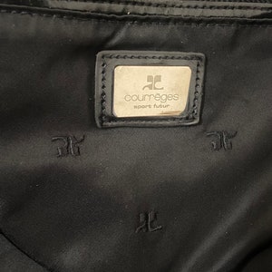 May include: Black nylon bag with a silver zipper and a silver logo patch that reads "Courr&egrave;ges sport futur".