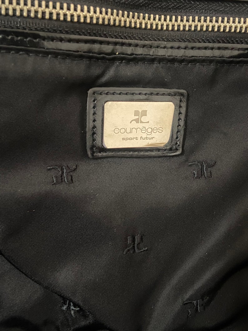 May include: Black nylon bag with a silver zipper and a silver logo patch that reads "Courr&egrave;ges sport futur".