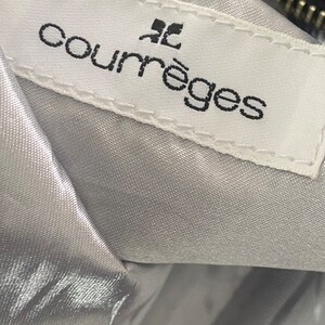 May include: A white label with black text that reads "Courr&egrave;ges" with a small black square above the word "Courr&egrave;ges".