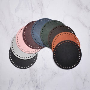 May include: A set of eight round leather circles in various colours, including black, brown, pink, green, and blue. The circles have evenly spaced holes around the edges.