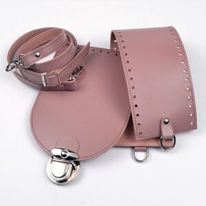 May include: A disassembled dusty rose leather bag kit. The kit includes a flap with a silver clasp, a body with pre-punched holes, a detachable shoulder strap, and silver metal hardware. The bag is designed for crafting and DIY projects.