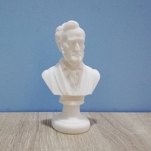 Può includere: Busto in gesso bianco di un uomo con la barba e i capelli corti. Il busto è su un piedistallo bianco.