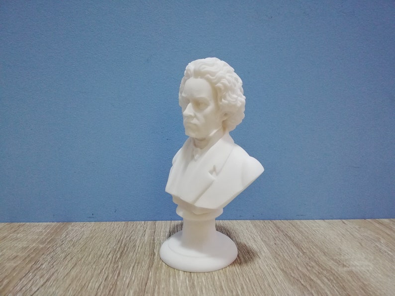May include: A white bust sculpture of a man with curly hair and a stern expression. The sculpture is on a pedestal base and set against a blue background. The bust is a classical art piece.