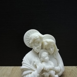 Puede incluir: Escultura de cer&aacute;mica blanca de la Sagrada Familia. La escultura representa a Mar&iacute;a, Jos&eacute; y el ni&ntilde;o Jes&uacute;s. Las figuras est&aacute;n representadas en un abrazo amoroso.