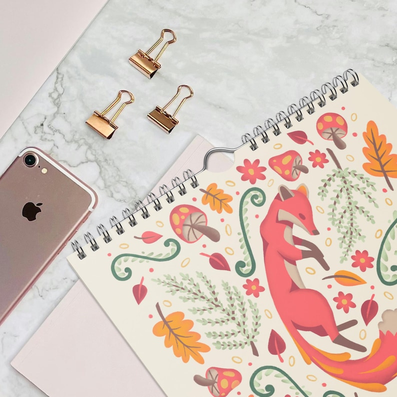 A 2026 wall calendar featuring colourful folk-art animal illustrations displayed in a flat lay. Wire-bound with premium thick paper, this illustrated monthly calendar showcases vibrant artwork for each month. Ideal for shoppers looking for a 2026 calendar, animal art calendar, home décor calendar, or unique artist-designed wall calendar.