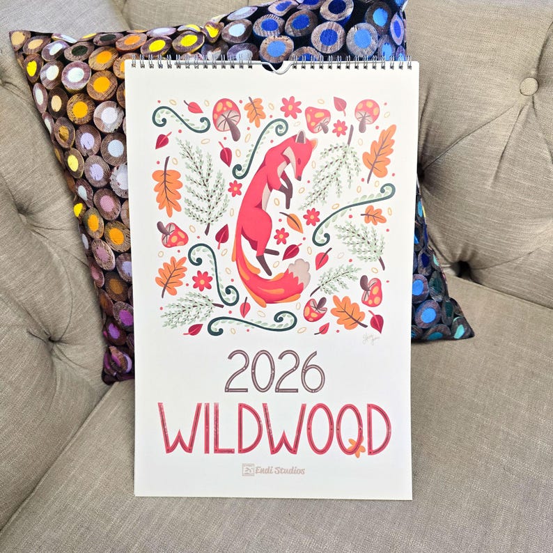 A 2026 wall calendar featuring colourful folk-art animal illustrations displayed in a flat lay. Wire-bound with premium thick paper, this illustrated monthly calendar showcases vibrant artwork for each month. Ideal for shoppers looking for a 2026 calendar, animal art calendar, home décor calendar, or unique artist-designed wall calendar.