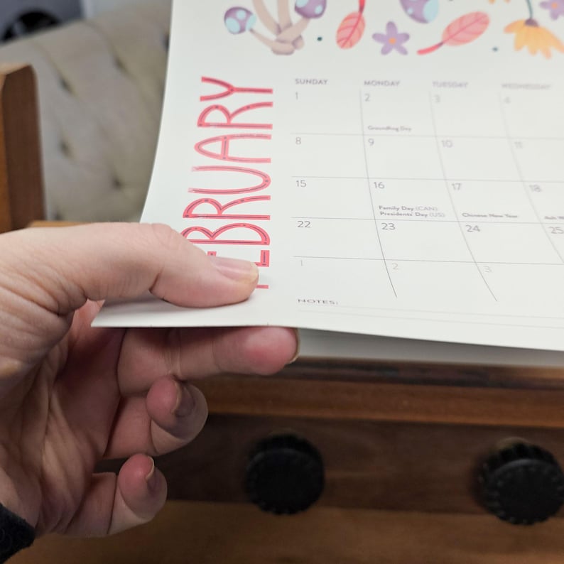 An upclose image of the paper for a 2026 wall calendar featuring colourful folk-art animal illustrations. Wire-bound with premium thick paper, this illustrated monthly calendar showcases vibrant artwork for each month. Ideal for shoppers looking for a 2026 calendar, animal art calendar, home décor calendar, or unique artist-designed wall calendar.