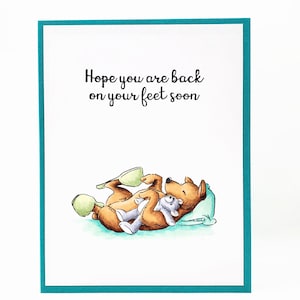 Dog in slippers hugging teddy bear get well card; Hope you are back on your feet soon