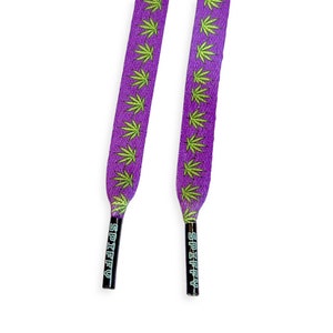 Könnte beinhalten: Lilafarbene Schnürsenkel mit einem grünen Marihuana-Blatt-Muster und dem Wort "SPIFFY" auf den Enden.