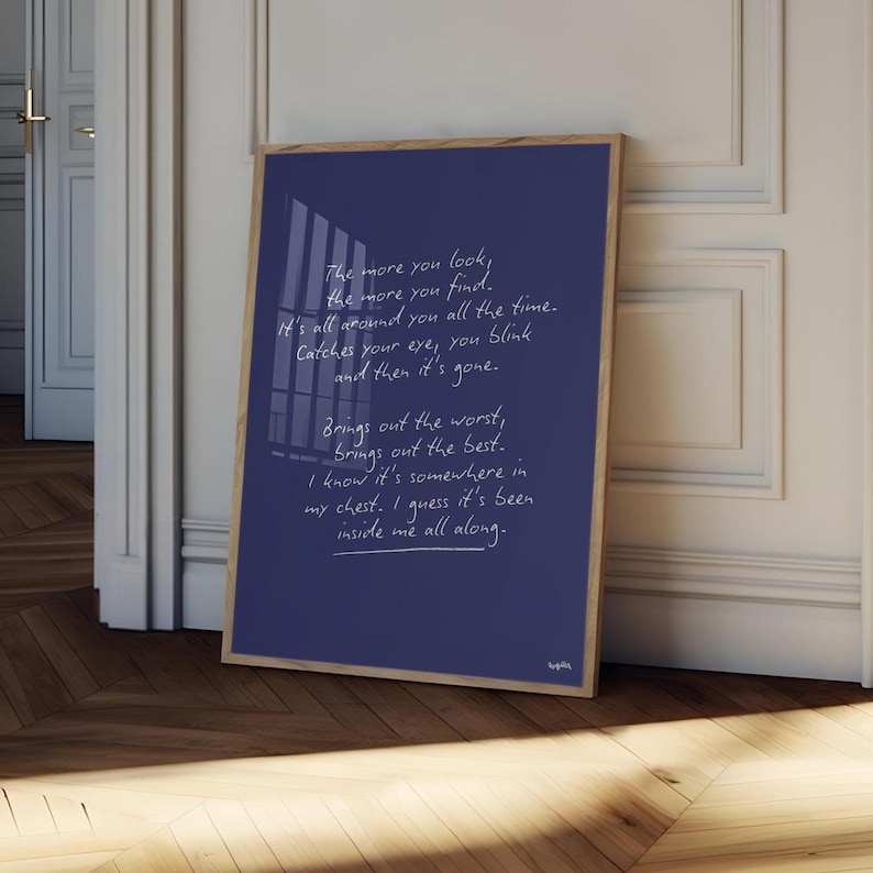 K&ouml;nnte beinhalten: Ein gerahmter Druck mit marineblauem Hintergrund und handgeschriebenem wei&szlig;em Text. Der Holzrahmen umgibt das Kunstwerk, das an einer wei&szlig;en Wand lehnt. Der Text enth&auml;lt S&auml;tze wie "The more you look, the more you find."