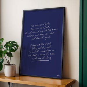 K&ouml;nnte beinhalten: Ein gerahmter Kunstdruck mit dunkelblauem Hintergrund und wei&szlig;em handgeschriebenem Text. Der Text lautet: &bdquo;The more you look, the more you find...inside me all along.&ldquo; Der Rahmen ist schwarz, und der Druck wird auf einer Holzoberfl&auml;che angezeigt.
