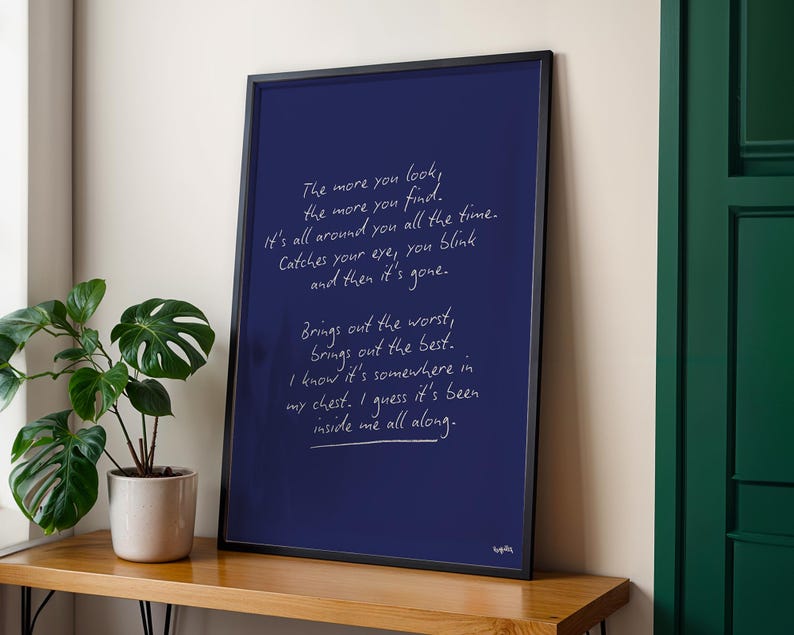 K&ouml;nnte beinhalten: Ein gerahmter Kunstdruck mit dunkelblauem Hintergrund und wei&szlig;em handgeschriebenem Text. Der Text lautet: &bdquo;The more you look, the more you find...inside me all along.&ldquo; Der Rahmen ist schwarz, und der Druck wird auf einer Holzoberfl&auml;che angezeigt.