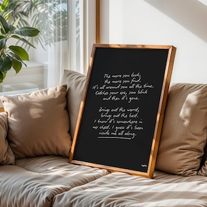 K&ouml;nnte beinhalten: Eine gerahmte schwarze Tafel mit handgeschriebenem wei&szlig;em Text. Der Holzrahmen umgibt die Tafel, die auf einem beigefarbenen Sofa mit Kissen steht. Der Text enth&auml;lt S&auml;tze wie "The more you look, the more you find."
