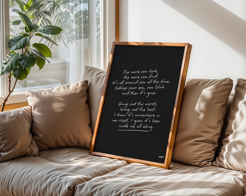 K&ouml;nnte beinhalten: Eine gerahmte schwarze Tafel mit handgeschriebenem wei&szlig;em Text. Der Holzrahmen umgibt die Tafel, die auf einem beigefarbenen Sofa mit Kissen steht. Der Text enth&auml;lt S&auml;tze wie "The more you look, the more you find."