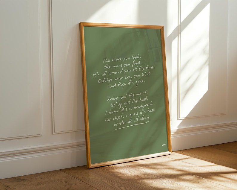 K&ouml;nnte beinhalten: Ein gerahmter Druck mit gr&uuml;nem Hintergrund und goldenem Rahmen. Der Druck zeigt handgeschriebenen wei&szlig;en Text mit einem Gedicht &uuml;ber das Finden von etwas, das schon immer da war. Der Rahmen lehnt an einer wei&szlig;en Wand und einem Holzboden.