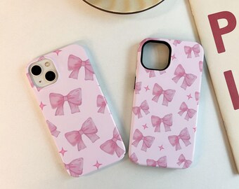 May include: Two pink phone cases with a pattern of pink bows on a white background.