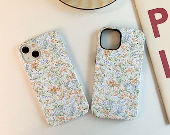 May include: Two white iPhone cases with a floral pattern. The pattern features small blue, orange, and green flowers on a white background.
