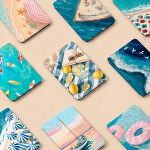 Pode incluir: Uma coleção de designs com tema de praia, incluindo uma cena de praia com um guarda-sol, um veleiro na água e um piquenique com limões e uma bebida. Outros designs apresentam ondas do oceano, pranchas de surf e um anel inflável rosa.