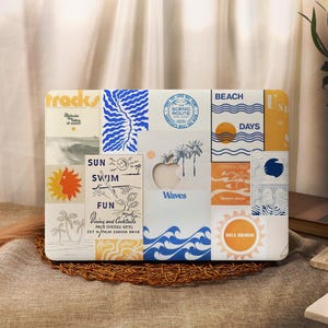 Könnte beinhalten: Ein Laptop-Computer, der mit bunten Aufklebern im Strandthema bedeckt ist. Die Aufkleber zeigen Texte wie "Sun Swim Fun", "Waves", "Beach Days" und "Take a Sunbreak".