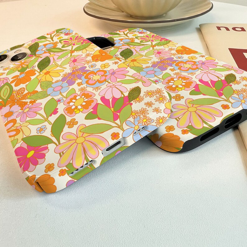 May include: Two phone cases featuring a vintage floral design in shades of pink, yellow, orange, blue, and green on a white background.
