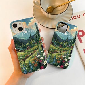 May include: Two phone cases with a landscape design featuring a mountain, trees, and a field of flowers. The cases have a blue sky background with clouds. The design includes a path, small houses, and colorful flowers.