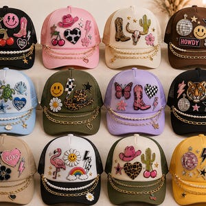 Pode incluir: Uma coleção de doze bonés trucker em várias cores, cada um decorado com diversos emblemas de tecido, incluindo estrelas, corações, animais e símbolos. Cada boné apresenta uma corrente decorativa e um fio de pérolas sobre a aba.