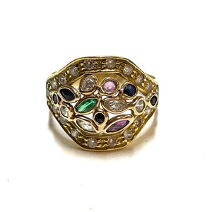 Könnte beinhalten: Ein goldener Ring mit einem mehrfarbigen Edelstein-Design. Der Ring verfügt über eine Vielzahl kleiner, runder Edelsteine in Weiß, Rosa, Grün und Blau, die in einem filigranen Golddesign eingefasst sind.