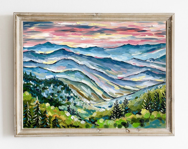 May include: A painting of a mountain landscape with a blue, green, and pink color scheme. The mountains are layered and the sky is a soft pink. The painting is framed in a light wood frame.
