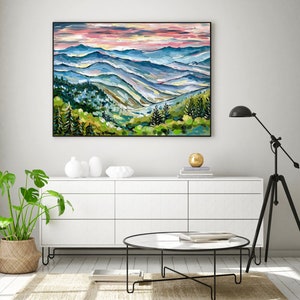 May include: A painting of a mountain landscape with a pink and blue sky. The mountains are painted in shades of blue, green, and brown. The painting is framed in black.