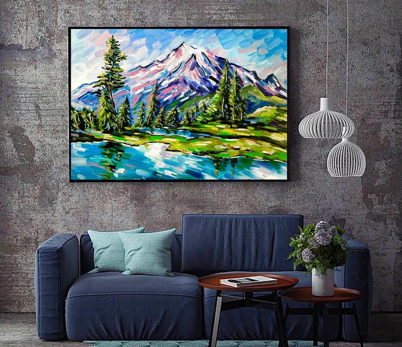 May include: A framed landscape painting depicts a mountain range with snow-capped peaks, lush green trees, and a serene blue lake. The artwork uses bold brushstrokes and vibrant colors, including blues, greens, and purples, to create a textured effect.
