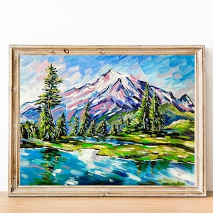 May include: Oil painting of a mountain landscape with a snow-capped peak, green trees, and a blue lake. The artwork is framed in a gold-colored wooden frame. The painting uses thick brushstrokes and vibrant colors.