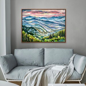 May include: A painting of a mountain landscape with a pink and purple sky. The mountains are painted in shades of blue and green, with a few trees in the foreground.