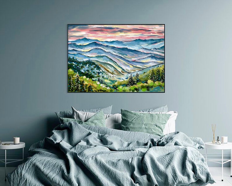 May include: A painting of a mountain range with a pink and purple sky. The mountains are painted in shades of blue, green, and brown. The painting is framed in black.