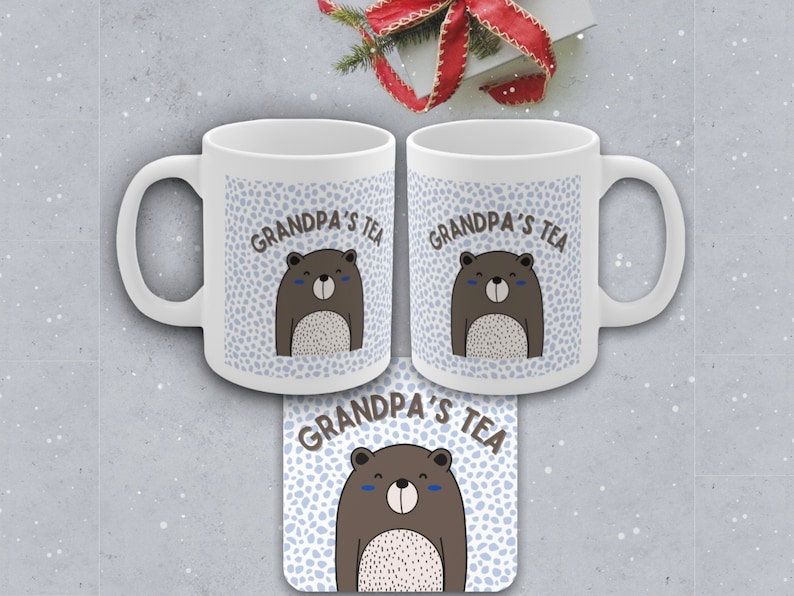 May include: Two white ceramic mugs with a blue and white pattern and a brown bear illustration. The mugs say "Grandpa's Tea" on them. A matching coaster with the same design is also shown.
