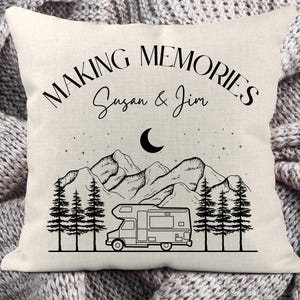 May include: A square off-white throw pillow featuring a black line art illustration of a camper van, pine trees, mountains, a crescent moon, and stars. The text reads "MAKING MEMORIES" and "Susan & Jim" in a black serif and script font.
