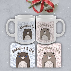 May include: Two white ceramic mugs with brown bear illustrations and the text "Grandpa's Tea" and "Grandma's Tea". Two matching coasters with the same design.