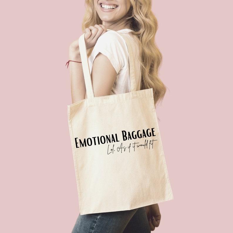 May include: A white canvas tote bag with black text that reads "Emotional Baggage Lol. As if it would fit."