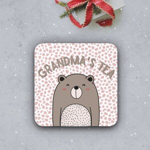 May include: A pink and white coaster with a brown bear and the text "Grandma's Tea".