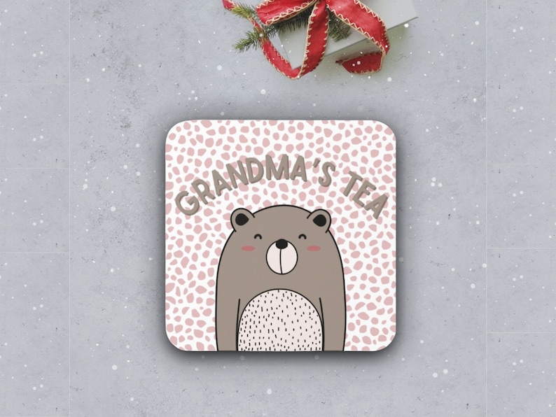 May include: A pink and white coaster with a brown bear and the text "Grandma's Tea".