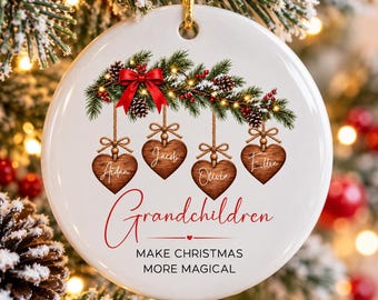 May include: A round white ceramic ornament featuring a festive pine branch with a red bow, pinecones, and berries. Four wooden heart-shaped tags hang from the branch, inscribed with the names Aidan, Jacob, Olivia, and Ellie. The text reads Grandchildren MAKE CHRISTMAS MORE MAGICAL.