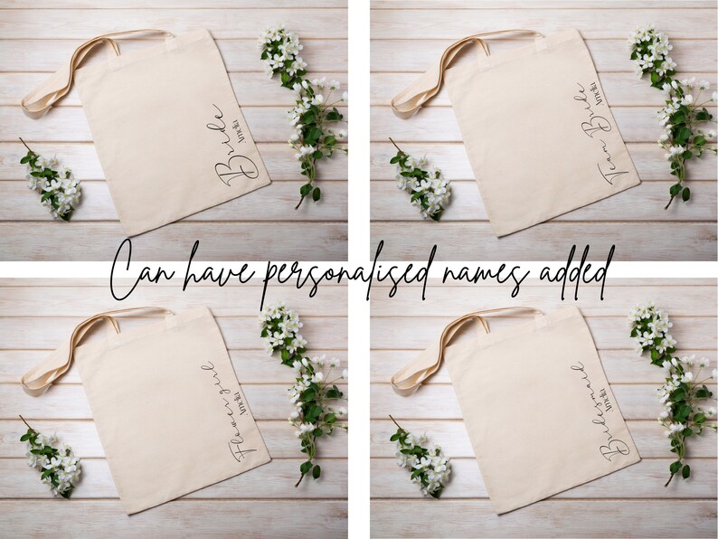 May include: Four beige tote bags with different text: "Bride", "Team Bride", "Flower Girl", and "Bridesmaid". Each bag has a cream-colored handle and is decorated with white flowers. The text "Can have personalised names added" is also present.