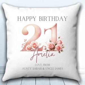 May include: White pillow with pink floral design and the text "Happy Birthday 21 Amelia Love from Aunty Sarah & Uncle James"