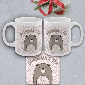 May include: Two white ceramic mugs with a brown bear and pink polka dot design. The text "Grandma's Tea" is printed on the mugs. A matching coaster with the same design is also shown.