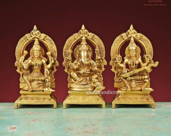 May include: Three gold-colored metal statues of Hindu deities on individual bases. The statues are of Lakshmi, Ganesha, and Saraswati, each with a halo behind their heads.