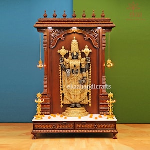 May include: A wooden shrine with intricate carvings, featuring a black and gold statue of a deity. The shrine has a white marble platform and two decorative lamps on either side.