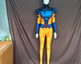 May include: A full-body costume in yellow and blue, featuring a black head covering and a red and black emblem on the chest. The costume has long sleeves and legs, with a design that mimics a superhero's outfit. The costume is displayed on a mannequin.