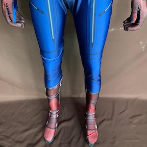 May include: Blue and red spandex costume with a zipper detail on the legs and boots. The boots are red with black and white details.