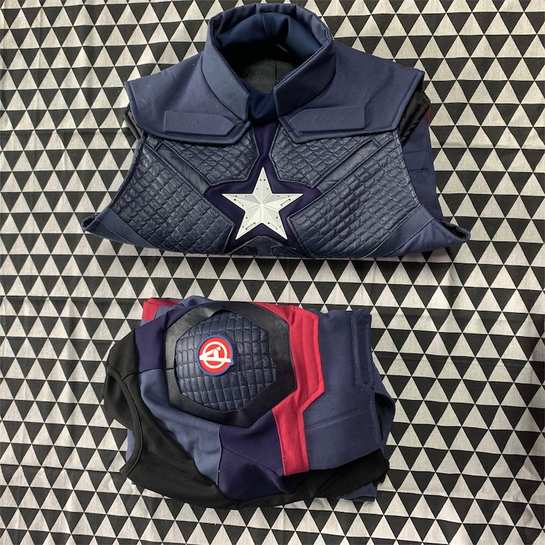 Pu&ograve; includere: Un costume da supereroe blu e rosso con una stella sul petto e una protezione per il ginocchio imbottita. Il costume &egrave; realizzato in un tessuto che sembra pelle.